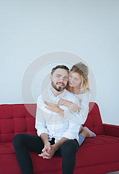 Couple in love woman hugging man on red sofa at home,Loving everything together,Happy and smiling