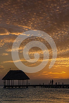 Couple in love at a wooden pier palapa enjoying Sunset at Holbox island near Cancun, Traveling Riviera Maya. Mexico adventure.