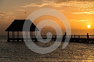 Couple in love at a wooden pier palapa enjoying Sunset at Holbox island near Cancun, Traveling Riviera Maya. Mexico adventure.