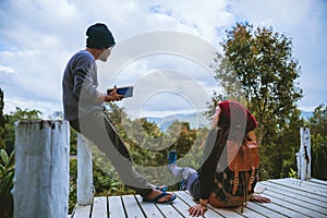 Couple lover natural travel on the mountain, sitting relax reading books in the midst of nature on the white wooden bridge