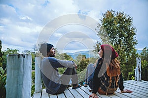 Couple lover natural travel on the mountain, sitting relax reading books in the midst of nature on the white wooden bridge