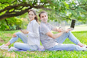 Couple of lover with technology device lifestyle, Using smartphone and laptop with green nature outdoor background