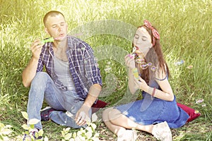 Couple lovers blow bubbles. friends laugh. summer picnic boy and girl are sitting on grass