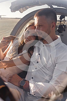 A couple of lovers, in the cockpit on their own plane. Smiling people and a private plane in the background.