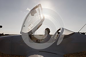 A couple of lovers, in the cockpit on their own plane. Smiling people and a private plane in the background.