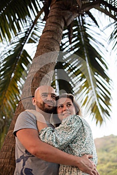 Couple of lovers hug under palm tree while relaxing in tropical paradise. Love and happiness. Tourism and travel.