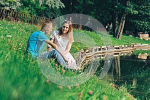 A couple of lovers on a lake in a romantic park.A happy young couple, a guy and a girl sitting on the grass near a river