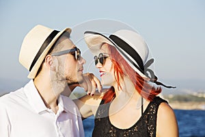 Beautiful couple of lovers sailing on a boat. Two fashion models posing on a sailing boat at sunset