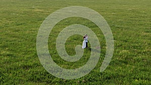 A couple of lovers stands in the middle of a field with green grass. They laugh, dance, kiss and inhale the aroma of