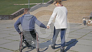 Couple lovers, Walk in park invalid on wheel chair and girlfriend,