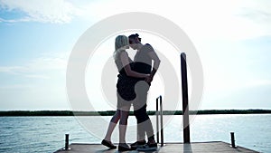 Couple of lovers walking along coast holding each other hand, tender couple kissing in sunlight