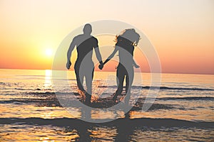 Couple of lovers walking inside water on tropical beach in summer vacation at sunset - Young people enjoying holidays - Love,