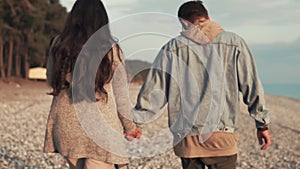 Couple of loving spouses walking along the shore near sea they are holding hands