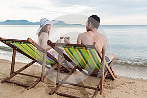 Couple luxury travel relaxation drink cocktail on chair tropical beach