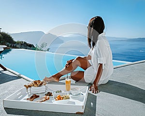 couple on a luxury vacation in Greece, Oia Santorini men and woman having breakfast at the pool