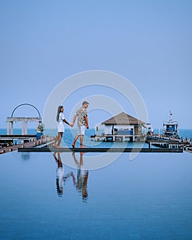 Couple on luxury vacation in Thailand, men and woman infinity pool looking out over the ocean