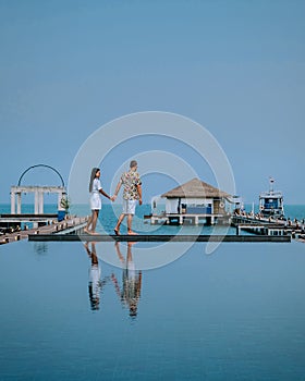 Couple on luxury vacation in Thailand, men and woman infinity pool looking out over the ocean