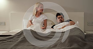 Couple lying and arguing on bed in bedroom.