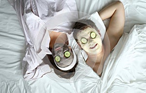 Couple lying on bed with cosmetic mask on face