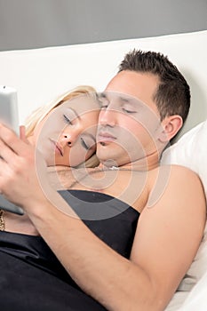 Couple lying in bed reading a tablet-pc