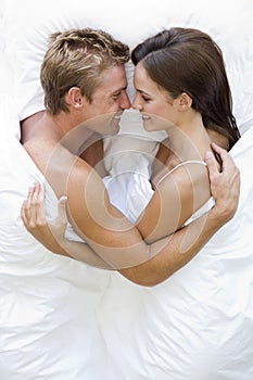 Couple lying in bed smiling