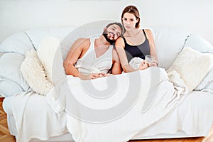 Couple lying on the couch and drinking coffee