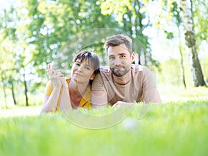 Couple lying down in grass looking to camera