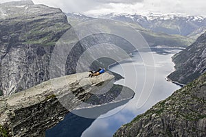 Couple lying down on trolltunga troll`s tongue rock , Norway
