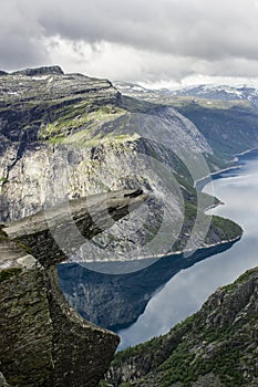 Couple lying down on trolltunga troll`s tongue rock , Norway