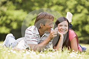 Couple lying outdoors with flower smiling