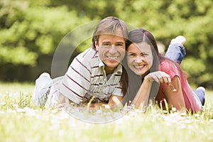 Couple lying outdoors with flower smiling