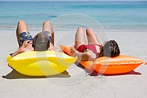 Couple lying on pool raft at beach