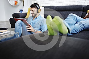 Couple Lying On Sofa With Tablet PC and Earphones