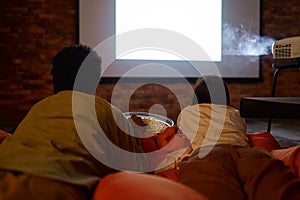 Couple lying on soft bag watching projector