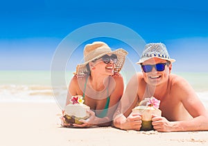 Couple lying at a tropical beach in Barbados and drinking a coconut cocktail