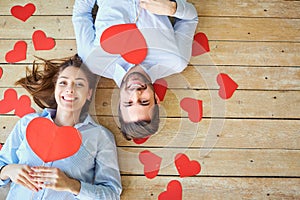 Couple lying on the wooden floor with hearts view from above.