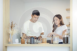 Couple make coffee in kitchen.