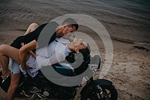 Couple makes love on beach lying on motorcycle
