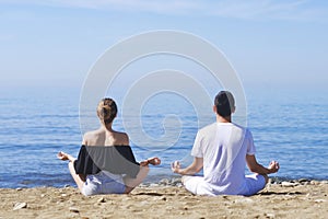 Couple makes meditation in lotus pose on sea / ocean beach, harmony and contemplation. Boy and girl practicing yoga at sea resort