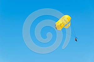 A couple makes parasailing on a sunny day. Parachuting above the clouds. Parasailing in a blue sky. Parachute walk on the sea