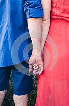 Couple makes a selfie while lying on the grass in flowers. Rest, lovers on a flower meadow. Bearded man and a girl in a red dress