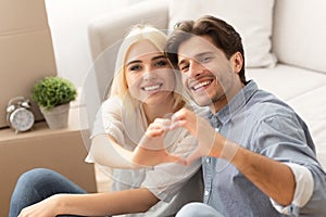 Couple Making Heart Shape With Their Hands In New Home