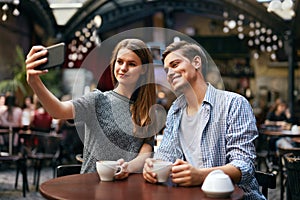 Couple Making Photo On Mobile Phone In Cafe