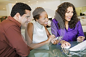 Couple Making Purchase Through Computer In Furniture Store