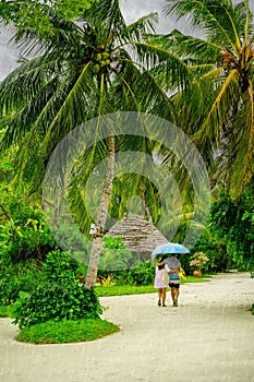 Couple in Maldives walking in the rain at lunchtime.