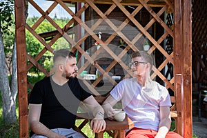 Couple of male friends look at each other on background of wooden pergola grid