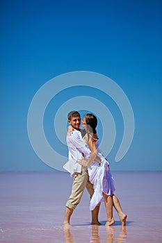 A couple a man and a woman dance on a pink lake on a Sunny day