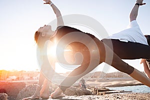 Couple man and woman doing yoga background sunlight blue sky and sea. Concept relaxation, harmony with nature