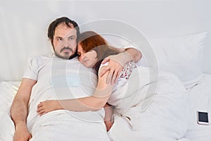 A couple a man and a woman are lying in an embrace in a white bed. Relationship problems coupled with isolation due to coronavirus