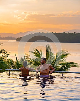 couple man and woman mid age in swimming pool on a luxury vacation in Thailand, men and Asian woman in pool looking out